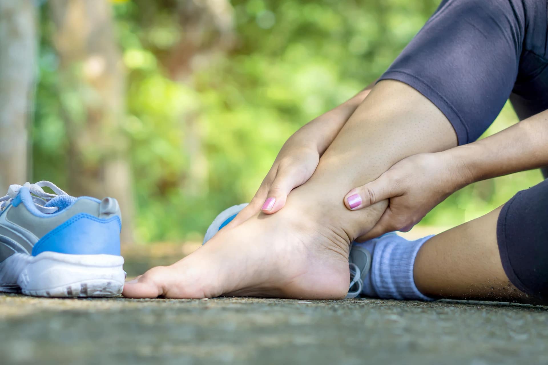Runner holding the back of their ankle and lower calf, illustrating tight calves and Achilles irritation relevant to dry needling in Preston